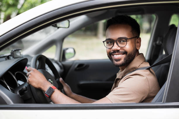 Smiling young man driving a car stock photo