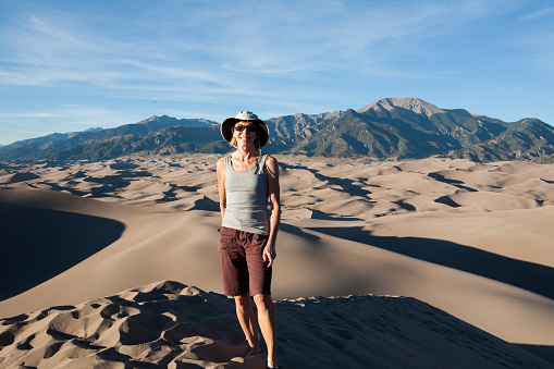 Fit mature woman standing on a large sand dune. Great Sand Dune National Park, Colorado.