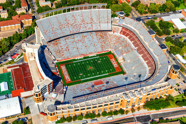 Lincoln, Nebraska, USA - June 25, 2024:Downtown Lincoln, Nebraska, features massive Memorial Stadium in the foreground, its distinctive horseshoe shape and red seats prominent. City skyline rises behind, blending modern office buildings, hotels, and the Nebraska State Capitol with its golden dome. University of Nebraska State Museum, Sheldon Museum of Art, Lied Center for Performing Arts, Hamilton Hall, Nebraska History Museum, U.S. Bank, UNL School of Biological Sciences rise above urban landscape