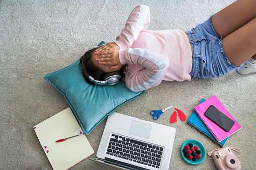 young girl lying on the carpet with laptop, smartphone and her things