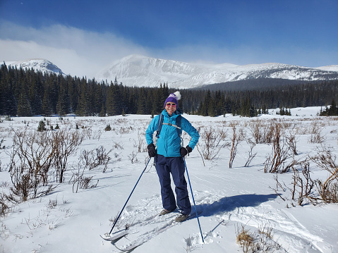 Mature woman breaking trail cross country skiing in Indian Peaks Wilderness Area, Colorado.