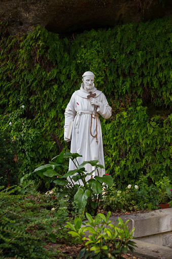 A view of a garden statue of Saint Francis of Assisi in a natural setting in the woods in brive la gaillarde in france