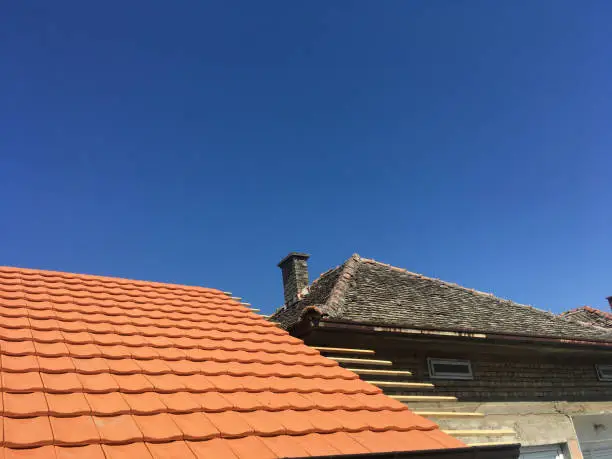 a new tiles roof and an old tiles roof with a blue sky in background