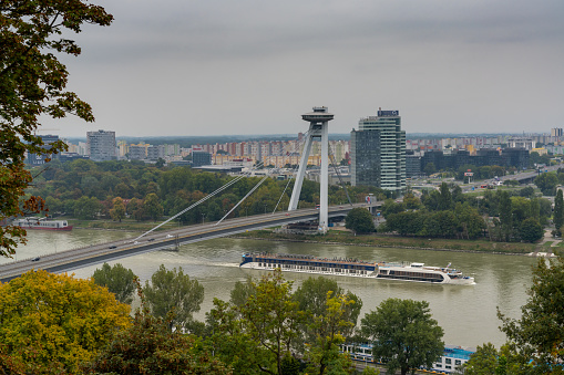 Bratislava, Slovakia - 25 September, 2022: a river cruise ship travels underneath the UFO Bridge on the Danube River in Bratislava