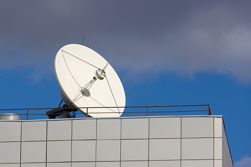 Satellite communications dish against blue sky.