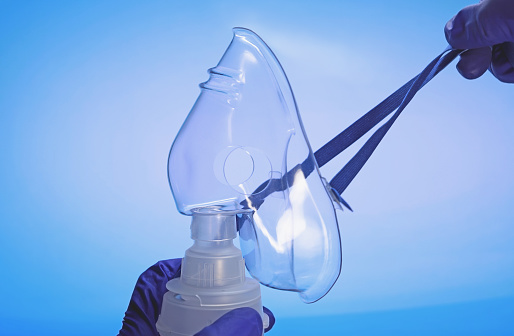 Mask of a compressor nebulizer in doctor's hands. Medical equipment. Mask of a nebulizer for inhalation during asthmatic attack. Breath difficulty therapy, Lung illness, Asthma.