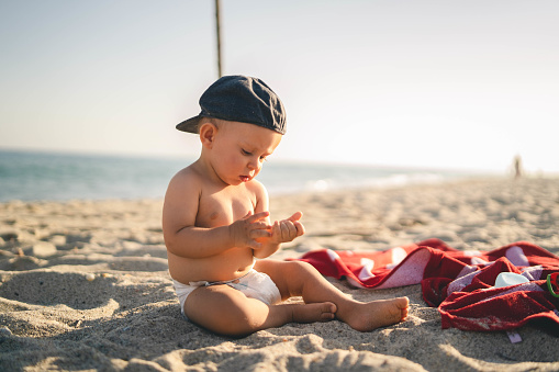 Little baby boy sitting on the sand