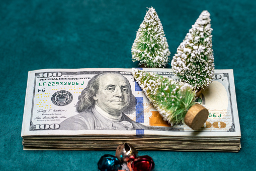 Vintage Bottle Brush Christmas Trees on top of USD Hundred Dollar Bills represent costs of holiday season