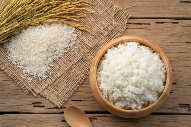 Cooked Thai rice in wooden bowl Cooked Thai rice in wooden bowl on wood background jasmine rice stock pictures, royalty-free photos & images