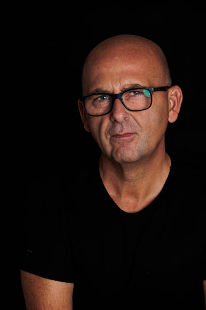 istock photograph man over 50 years bald with black background 1429416589