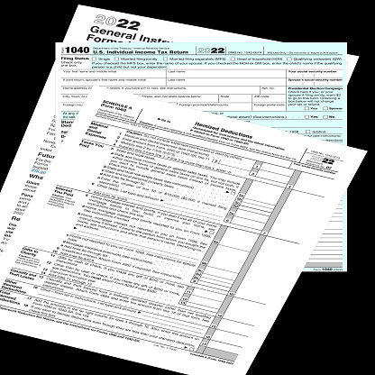 2022 IRS 1040 & 'schedule a' tax forms on a black desktop.