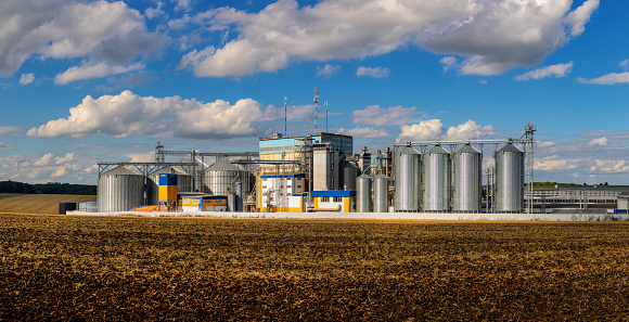 Agricultural Silos. Storage and drying of grains, wheat, corn, soy, sunflower against the blue sky with white clouds.Storage of the crop