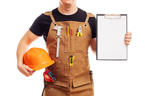 Contractor worker or carpenter in workers apron with helmet showing blank clipboard isolated on white background