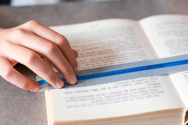 istock Reading tools for dyslexia. Child reading book using colorful ruler overlay strips. Education, learning disability, reading difficulties concept 1429434645