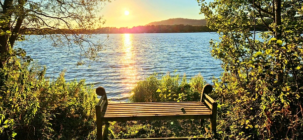 Sunset view from a bench overlooking a lake.