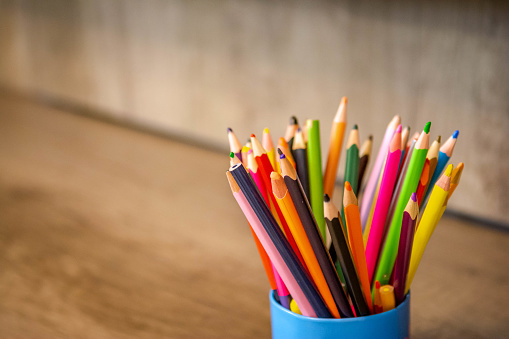 Rainbow colored pencils in classroom on brown table