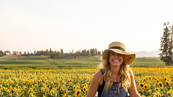 Beautiful woman smiles in Okanagan sunflower field - Armstrong, British Columbia