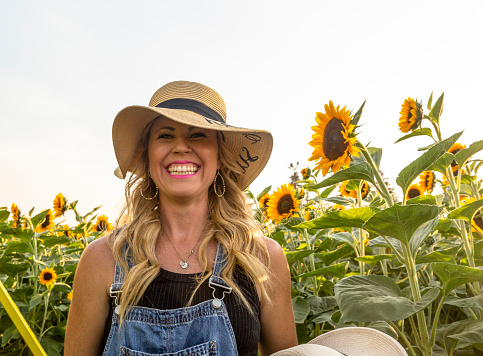 Happy beautiful young woman smiles in sunflower field