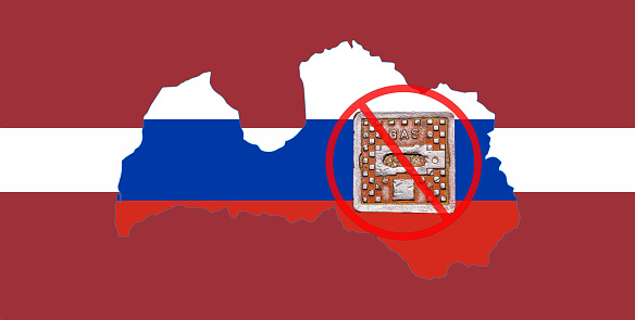 Outline map of Latvia with the image of the national flag. Manhole cover of the gas pipeline system on the flag of Russia inside the map. Collage. Energy crisis.