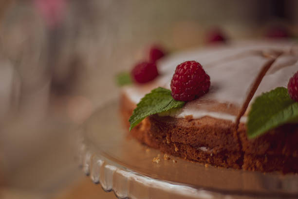 istock cake with white icing decorated with fresh raspberries and mint leaves on a wooden table in a cafe 1429452535