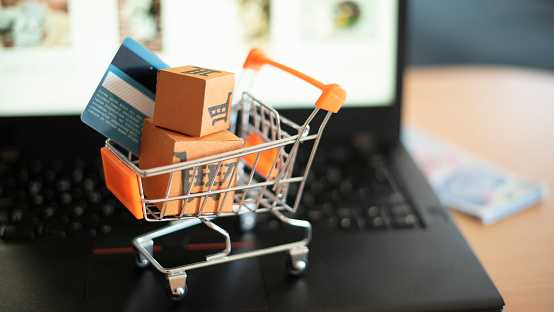 Is the payment cash or credit card? Shopping trolley and small boxes on laptop.
