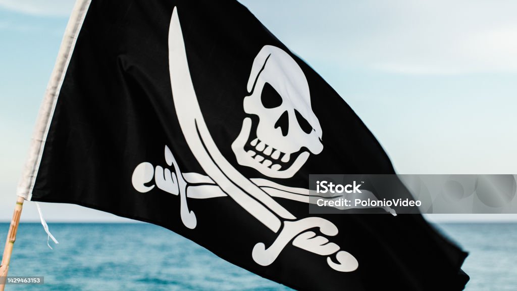 Black pirate flag with skull symbol on the desert island the black pirate flag with skull symbol waving on the beach near the ocean. Allegory Painting Stock Photo
