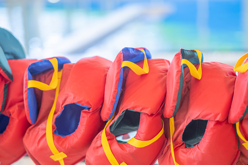 A group of life jackets hang poolside before a lesson