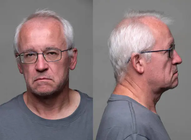 Serious  senior man front and profile mugshots on gray background