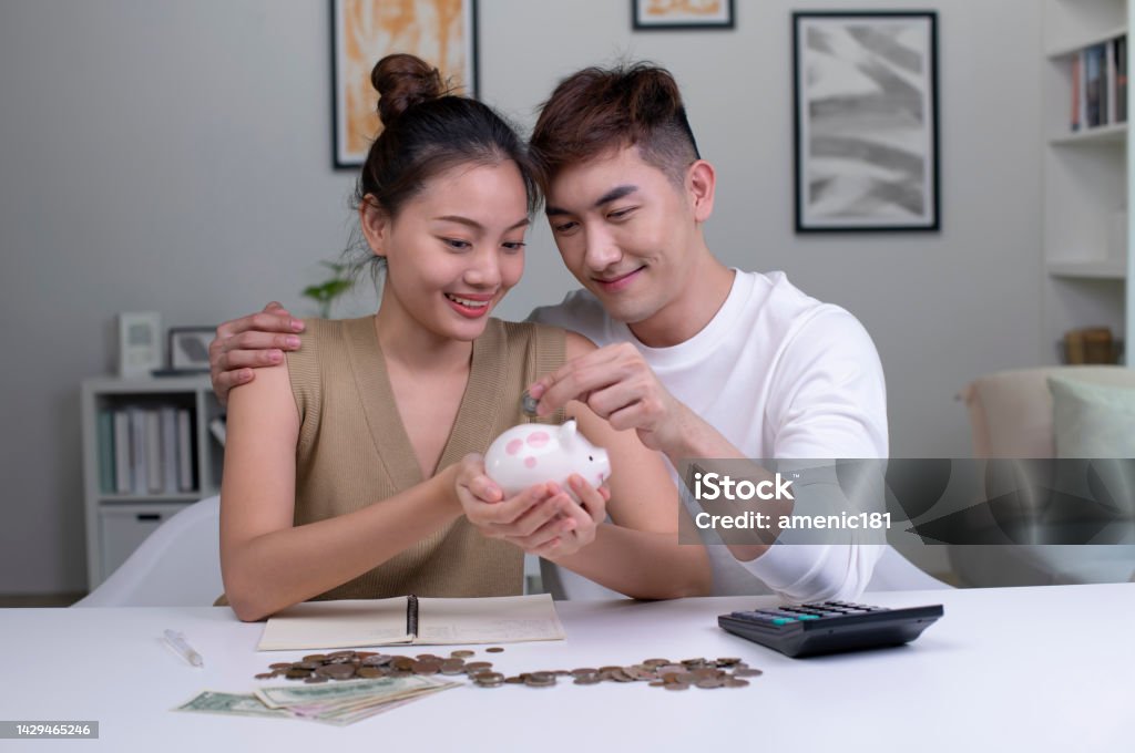 Female and male couple saving money for family and home. Young  Asian couple saving money to buy a house. Female and male couple saving money for family and home. 20-24 Years Stock Photo