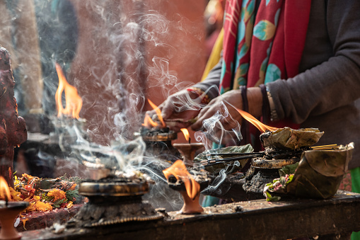 Narayanthan, Kathmandu, Nepal - nov 6, 2019: hands of pilgrims and Hindu devotees make ritual offerings among the fumes of incense and votive candles in the Hindu temple Budhanilkantha in Kathmandu