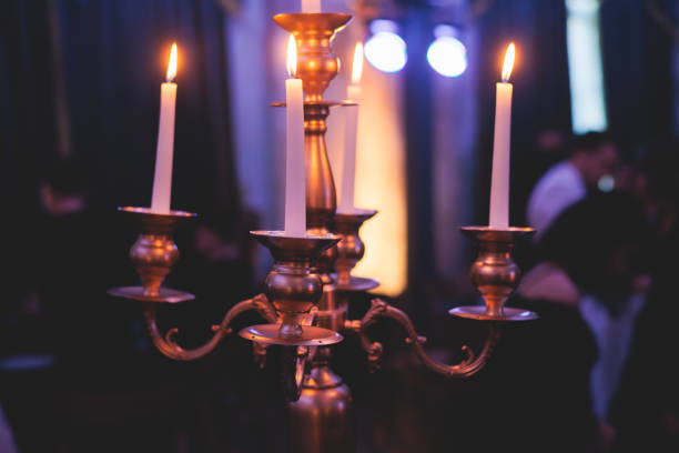 istock Vintage retro brass candlesticks with candles burning, luxury event banquet table setting decoration in a restaurant hall, atmosphere with candleholder, candle fire with guests on masquerade party 1429485378