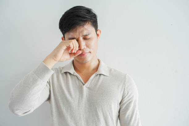close up young man using hand to rubs eye after feeling uncomfortable sensation for health care concept