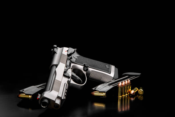 istock Silver black modern gun and ammunition for it on adark  background. Short-barreled weapons for sports and self-defense. Armament for police units, special forces and the army. 1429487008