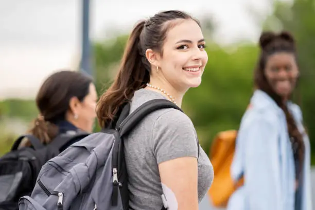 A girl smiles as she walks with her backpack on and wears an adhesive patch on her arm so that she can monitor her blood sugar level.