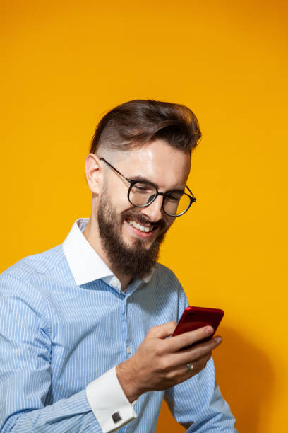 Studio portrait of a white 30 year old bearded man with glasses on a yellow background stock photo