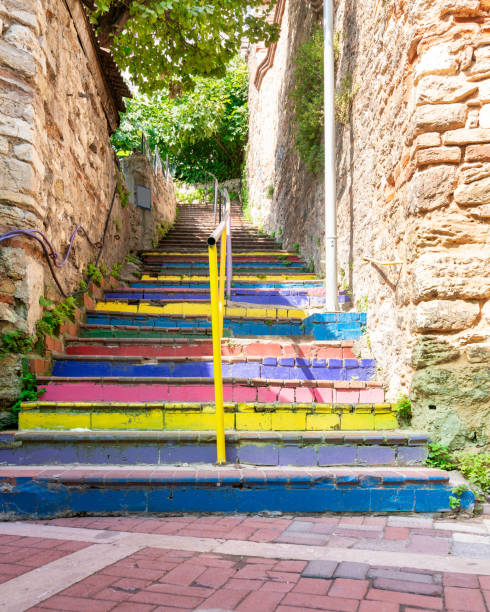 pasarela con escaleras de colores entre muros de piedra que conducen a antiguos edificios tradicionales en un día soleado - staircase steps istanbul turkey fotografías e imágenes de stock
