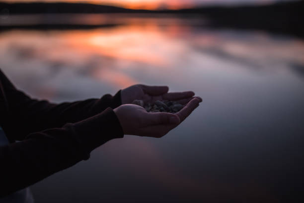 istock Unrecognizable woman holding pebbles while standing on lakeshore 1429494050