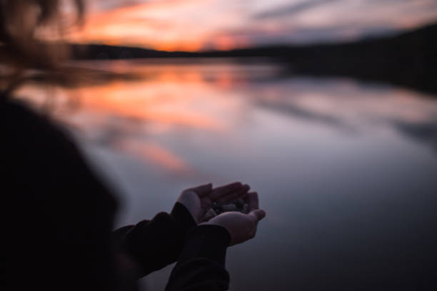 istock An unrecognizable woman holds pebbles in her hands while standing by the lake during sunset 1429494116
