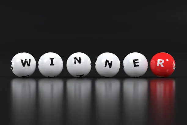 Six horizontally placed lottery balls on a dark background spelling the word winner