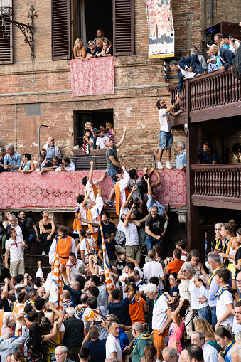Siena, Tuscany, Italy - August 17 2022: Palio Victory Celebration with Members of the Leocorno Contrada Receiving the Drappellone Trophy Banner.
