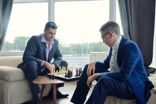 istock dad and son are sitting at a table by a wide window and playing chess making moves with pieces 1429547867