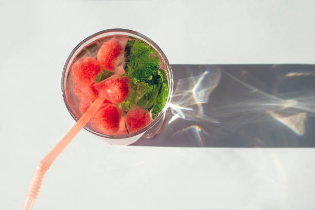 Lemonade with mint and watermelon on a white background with a beautiful shadow of the glass.