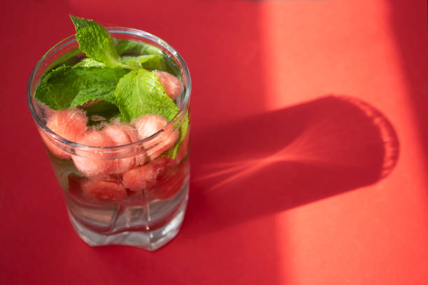 Detox water with watermelon balls and mint on a red background. Copy space for text.