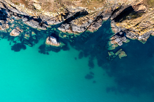 Vista aérea directamente sobre el escarpado acantilado costero afloramiento en el tranquilo océano turquesa photo