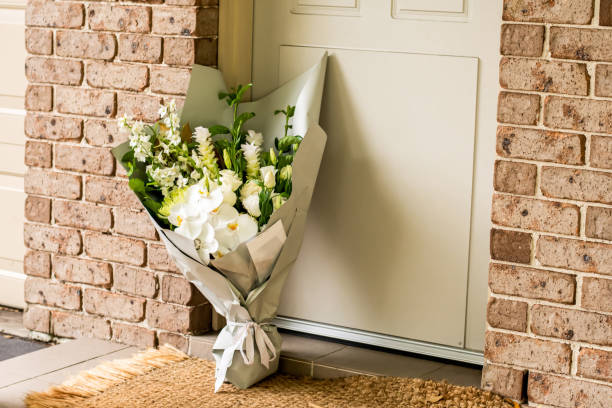 ein blumenstrauß, der auf einer veranda vor der haustür eines hauses geliefert wird. überraschender kontaktloser versand. muttertag, valentinstag, geburtstag, feier und jubiläumskonzept - türschwelle stock-fotos und bilder