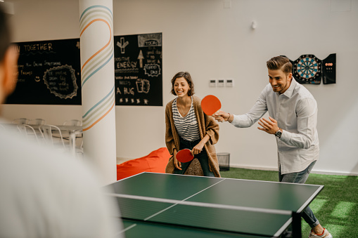 Group of young startup business people playing ping pong tennis at a modern creative office. Creative minds relaxing at work