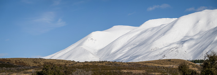 Panorama view of Ohau range covered in snow against a blue sky. Twizel, Mackenzie district, South Island.