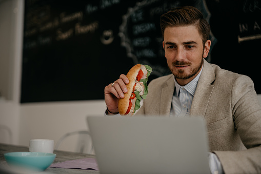 Shot of a young businessman eating takeout at his desk in a modern office.