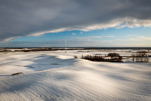 Wind turbine on snowy field in winter. Alternative energy. Aerial view of nature in Poland