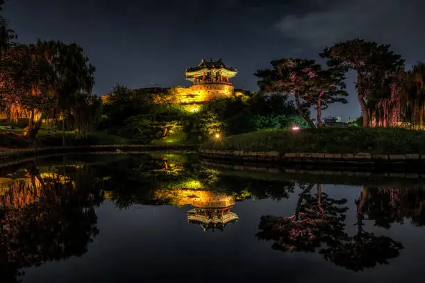 Banghwasuryujeong pavilion of Hwaseong Fortress captured at night  with the reflections on the yongyeon pond water. Famous pavilion in Suwon, South Korea